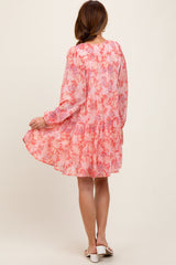 woman wearing a pink floral long sleeve dress with a tiered skirt and flowy silhouette
