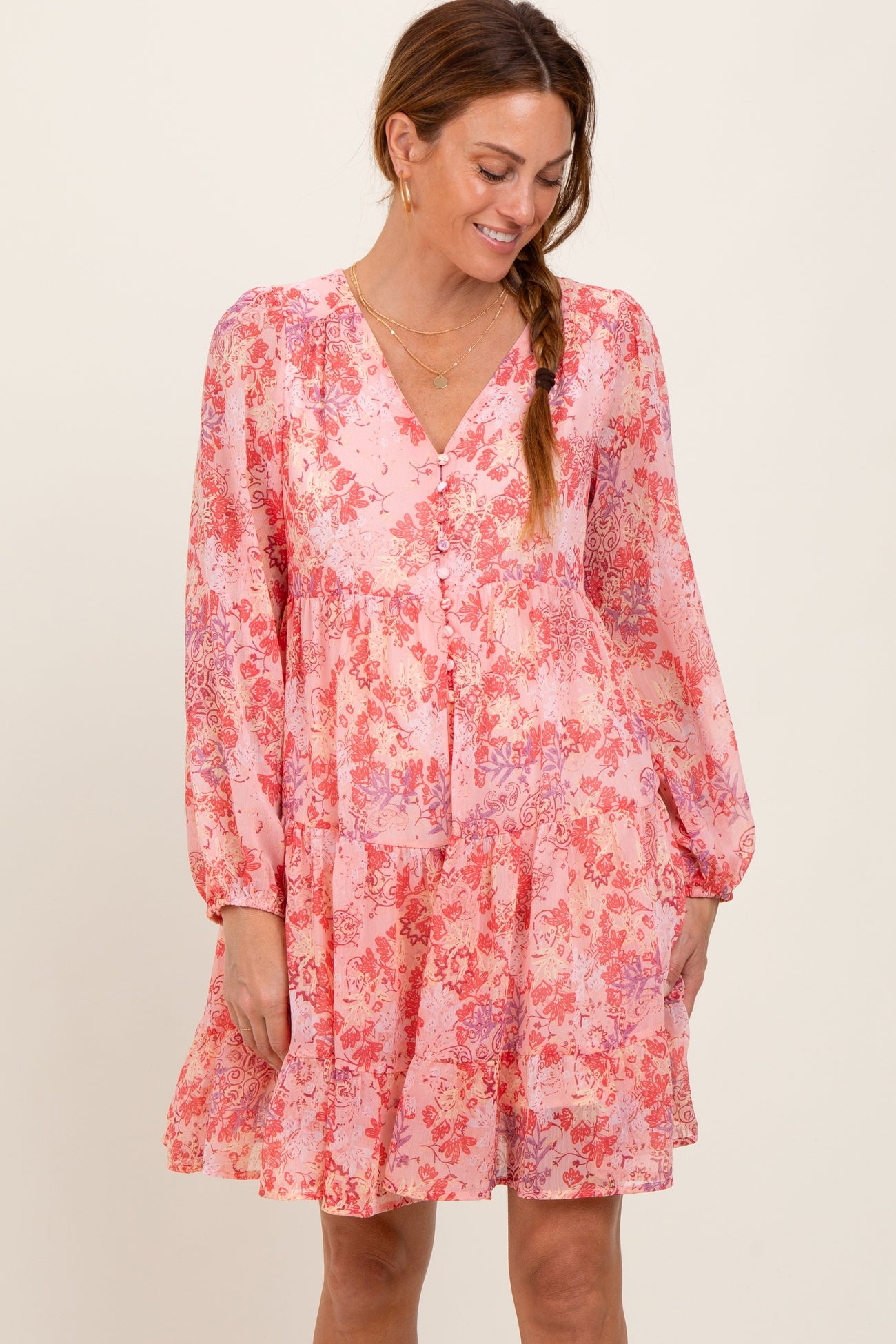 woman wearing a pink floral long sleeve dress with a v-neck and ruffled skirt