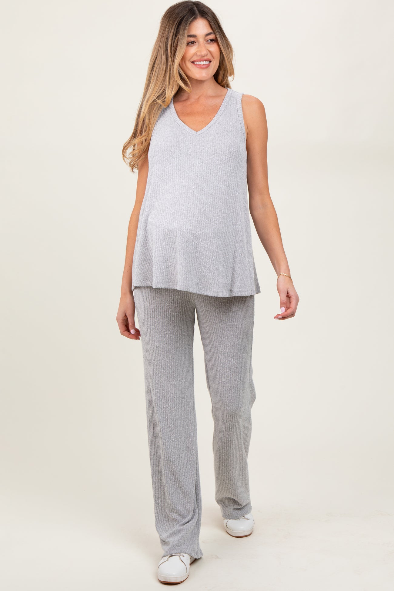 woman wearing a light gray ribbed maternity top and matching pants, showing her baby bump
