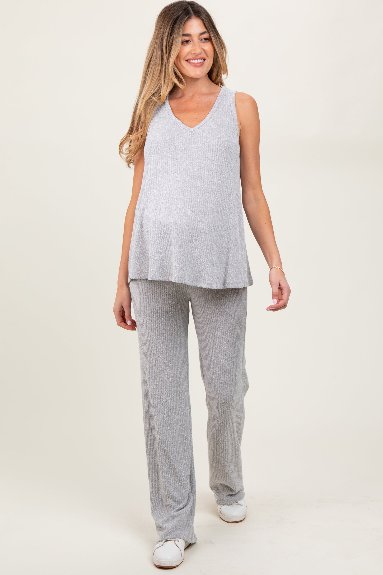 woman wearing a light gray ribbed maternity top and matching pants, showing her baby bump