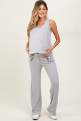woman wearing a gray v-neck maternity top and matching pants, showing her baby bump and smiling