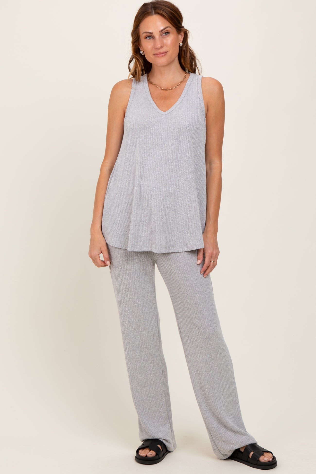 woman wearing a light gray sleeveless v-neck top and matching wide-leg pants, styled casually with sandals