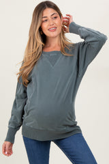 woman wearing a green maternity sweatshirt with a relaxed fit and long sleeves, showcasing her baby bump