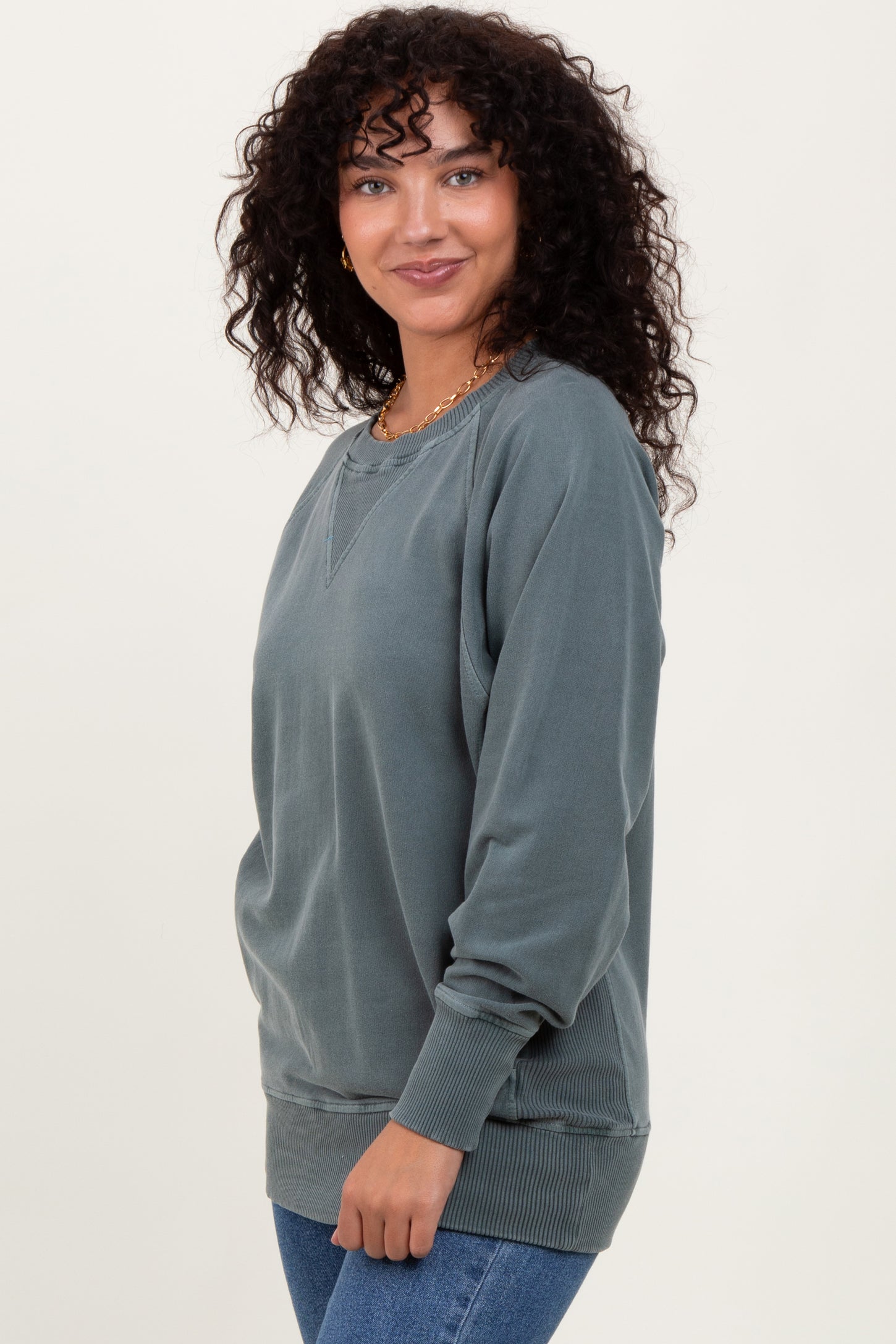 woman wearing a dusty blue oversized sweatshirt with ribbed cuffs and hem, styled casually with jeans