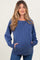 woman wearing a blue maternity sweatshirt with a relaxed fit and front pockets, showcasing her baby bump