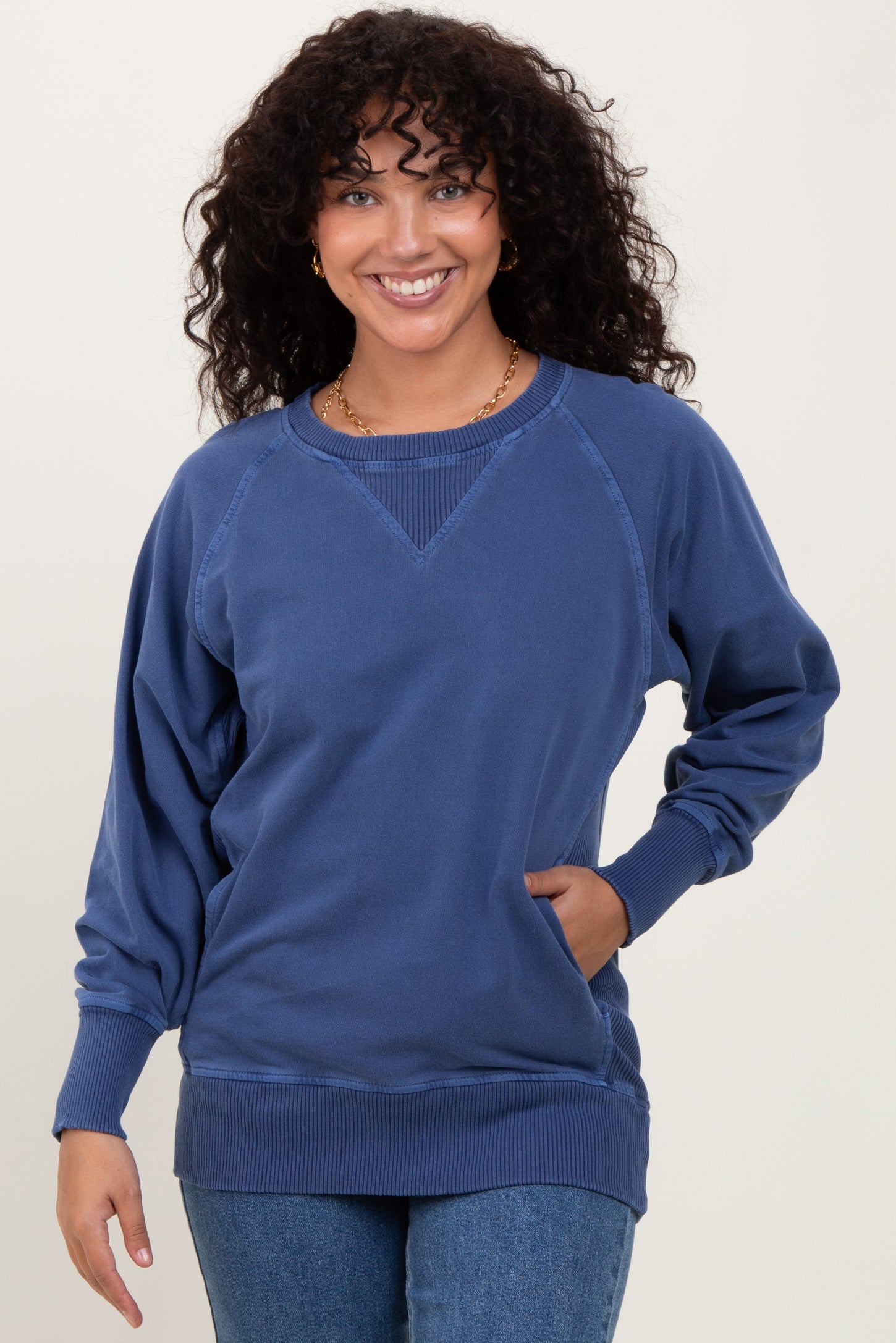 woman wearing a navy blue oversized sweatshirt with raglan sleeves and a rounded neckline