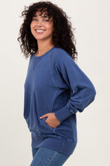 woman wearing a blue oversized sweatshirt with side pockets and a relaxed fit, smiling at the camera