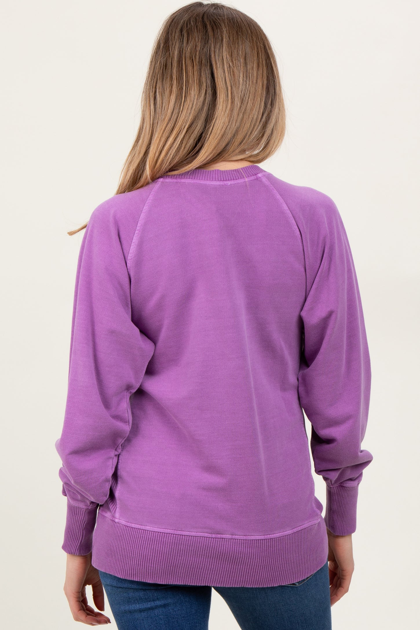 woman wearing a purple long sleeve maternity sweatshirt with a relaxed fit and ribbed hem, viewed from the back
