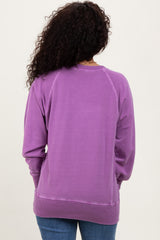 woman wearing a solid purple sweatshirt with a relaxed fit and ribbed cuffs, viewed from the back