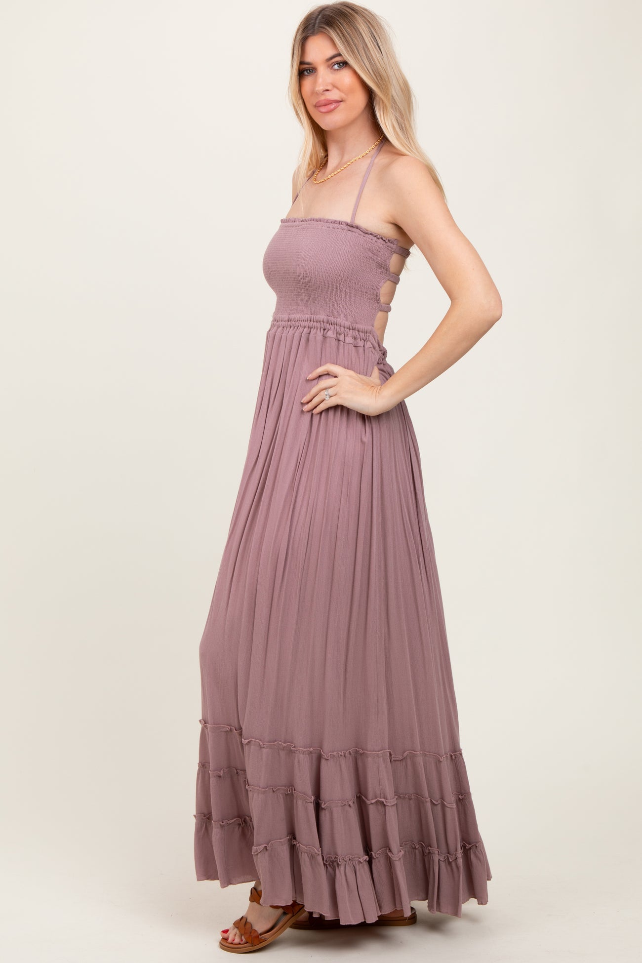 woman wearing a mauve sleeveless maxi dress with a smocked bodice and ruffle hem, posed sideways