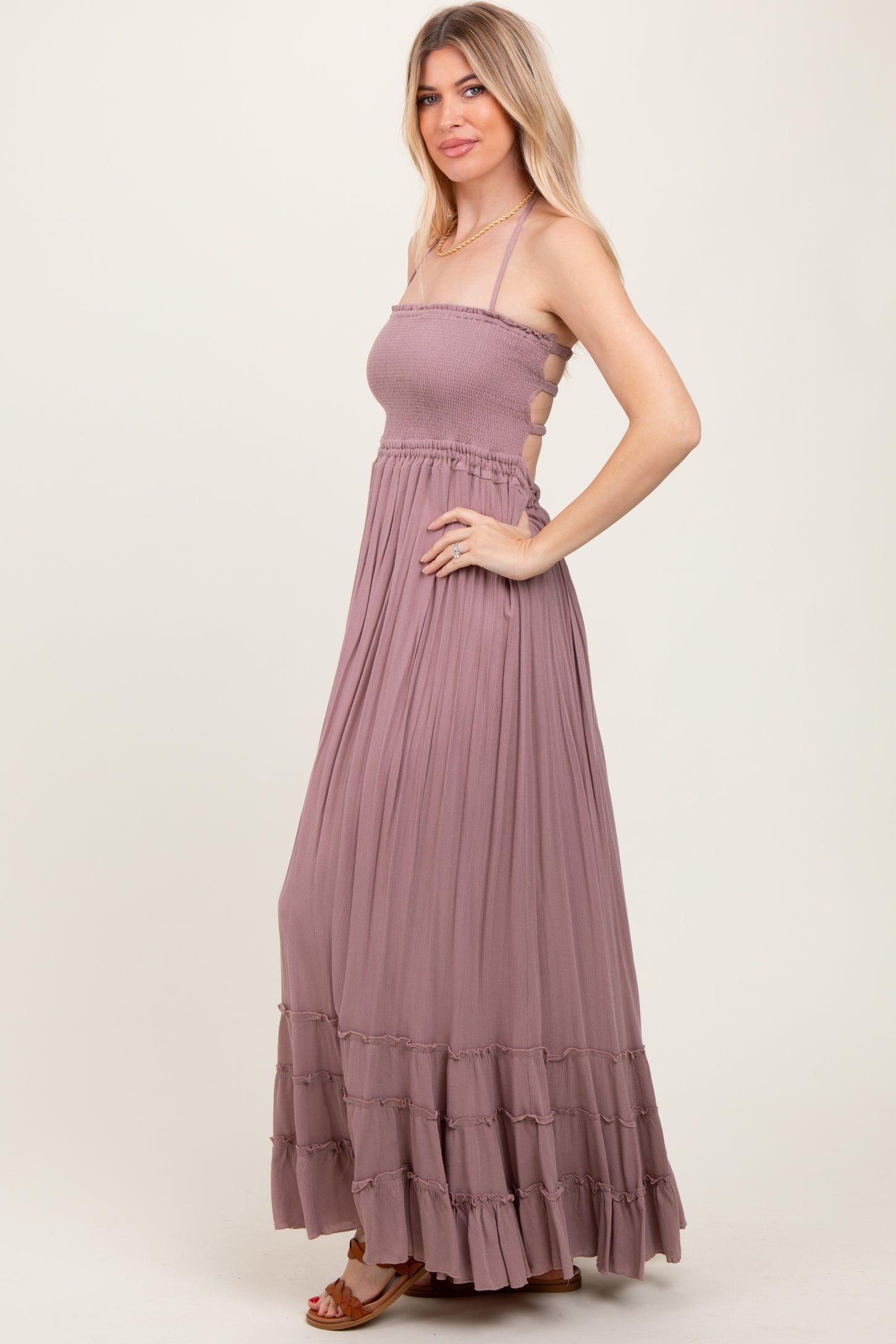 woman wearing a mauve sleeveless maxi dress with a smocked bodice and ruffle hem, posed sideways