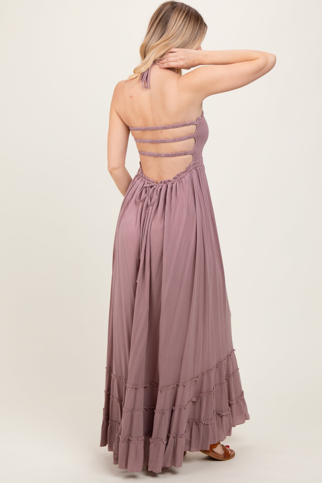 woman wearing a lavender halter neck maxi dress with a tiered ruffle hem and strappy back details