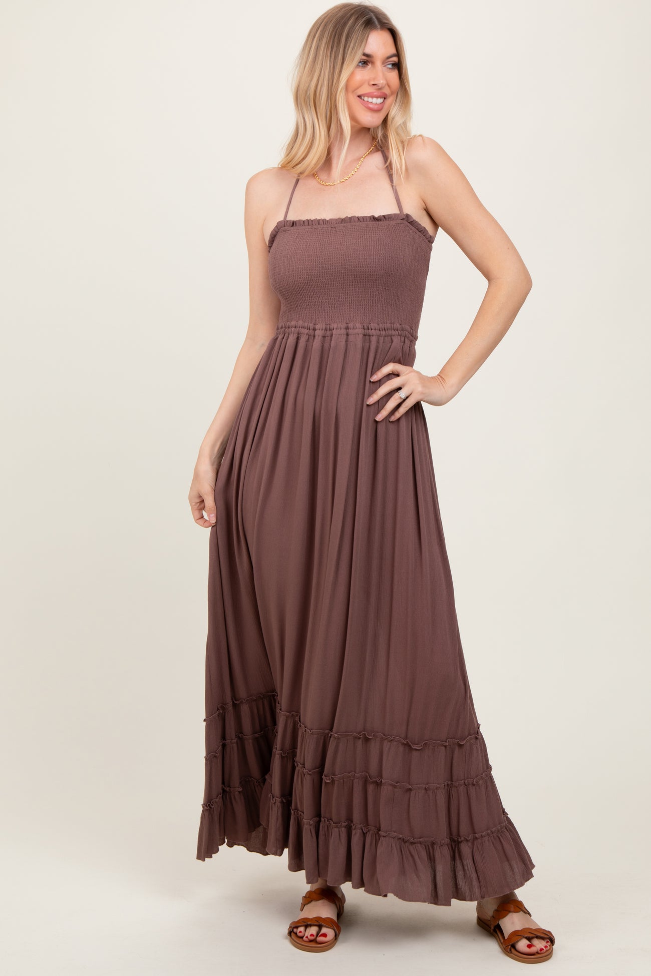woman wearing a brown sleeveless maxi dress with ruffle hem and smocked bodice