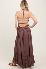 woman wearing a dusty mauve maxi dress with a halter neck and ruffled hem, showcasing an open back design