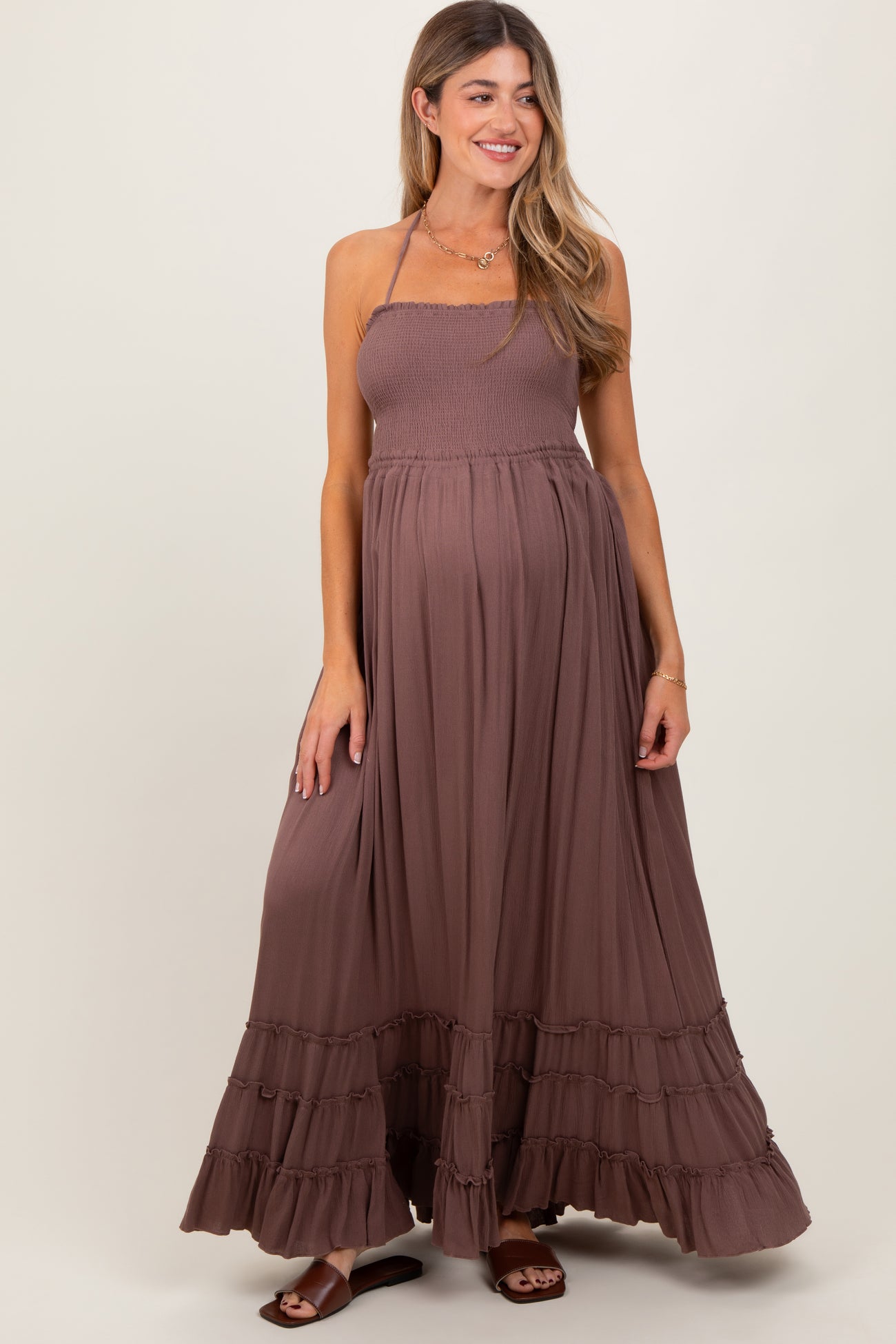 woman wearing a brown maternity maxi dress with a smocked bodice and ruffled hem, showcasing her baby bump