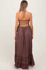 woman wearing a mauve maternity maxi dress with a halter neck and ruffled hem, showing a baby bump