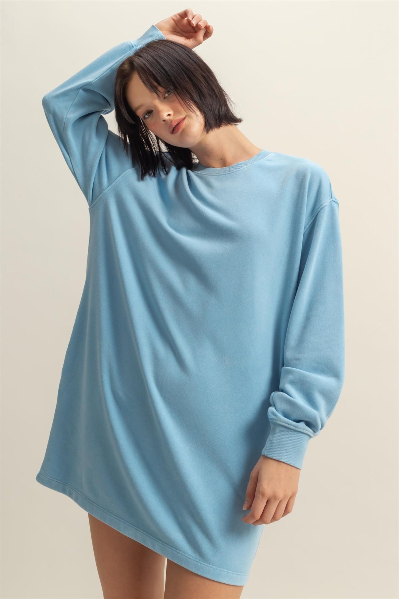 woman wearing a light blue oversized sweatshirt dress with long sleeves and a relaxed fit