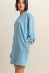 woman wearing a light blue long sleeve oversized sweatshirt dress with side pockets