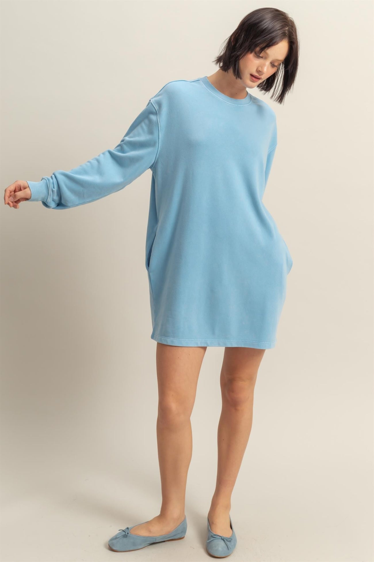 woman wearing a light blue oversized sweatshirt dress with long sleeves and pockets