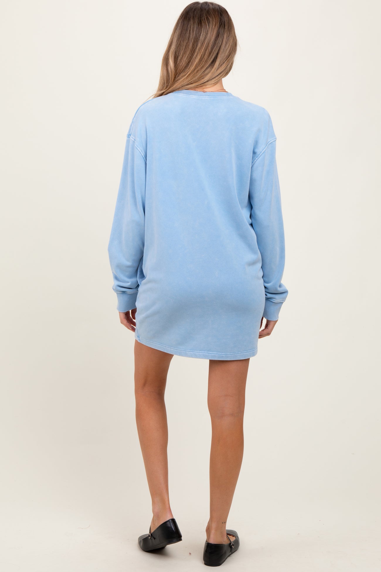 woman wearing a light blue maternity sweatshirt dress, showing a relaxed fit and long sleeves from the back