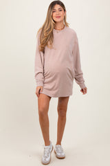 woman wearing a blush pink maternity sweatshirt dress with a visible baby bump and white sneakers