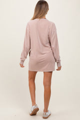 woman wearing a light pink maternity dress with long sleeves, standing with her back to the camera