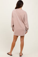 woman wearing a light pink oversized sweatshirt dress, showing the back view with long sleeves and relaxed fit