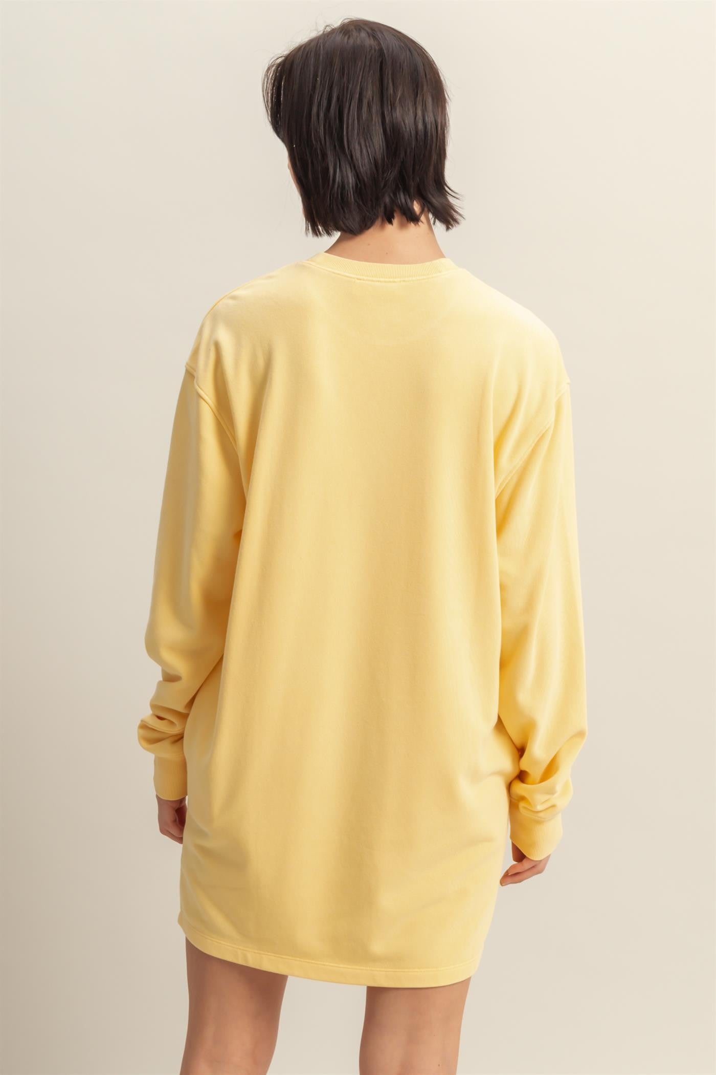 woman wearing a yellow oversized long sleeve t-shirt dress, viewed from the back