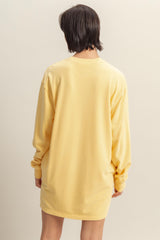 woman wearing a yellow oversized long sleeve t-shirt dress, viewed from the back