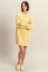 woman wearing a loose-fitting yellow oversized sweatshirt dress and checkered slip-on shoes