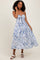 woman wearing a blue and white tie-dye midi dress with a front tie detail and spaghetti straps