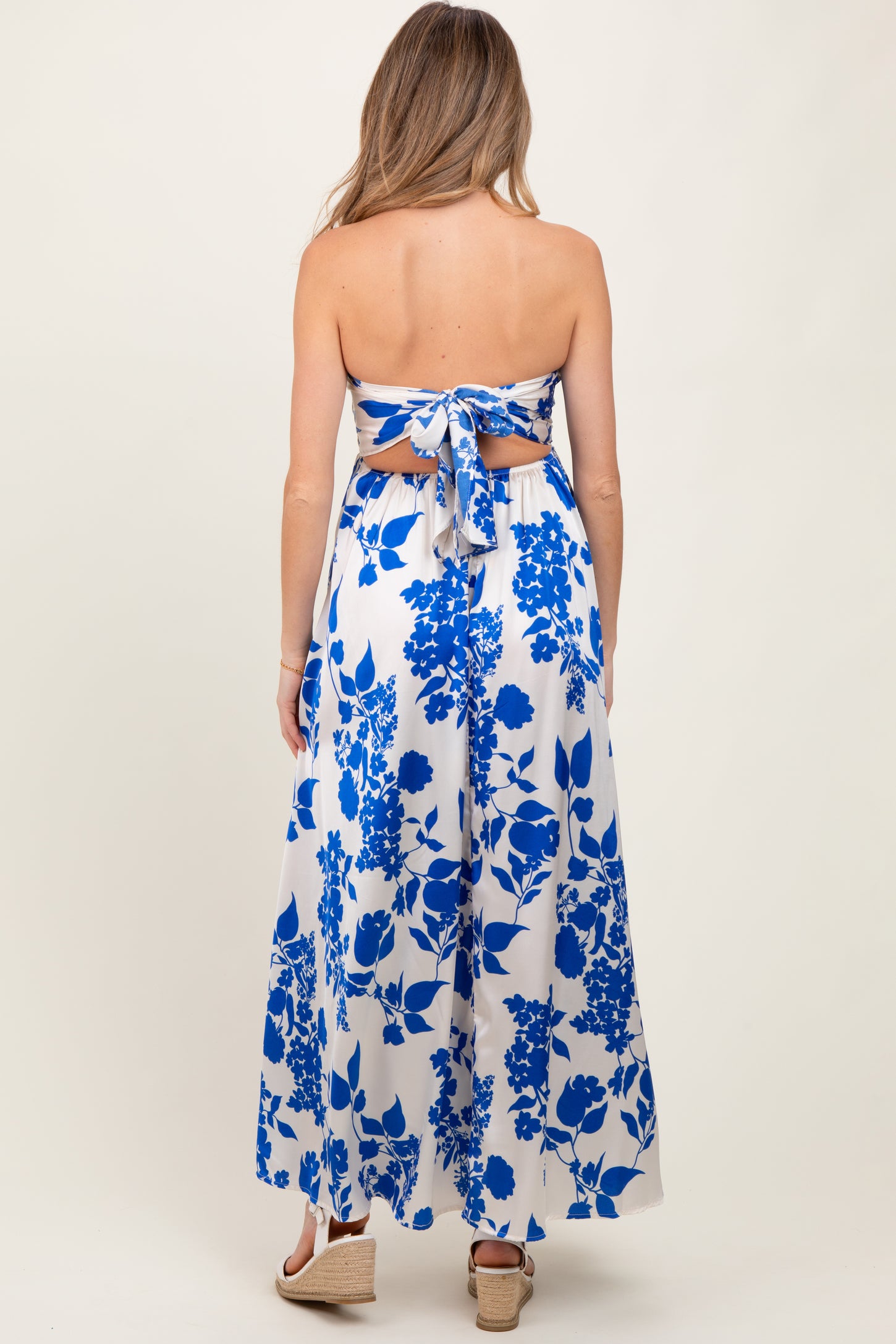 woman wearing a blue and white floral strapless maternity maxi dress with a tied back detail and a flowing silhouette