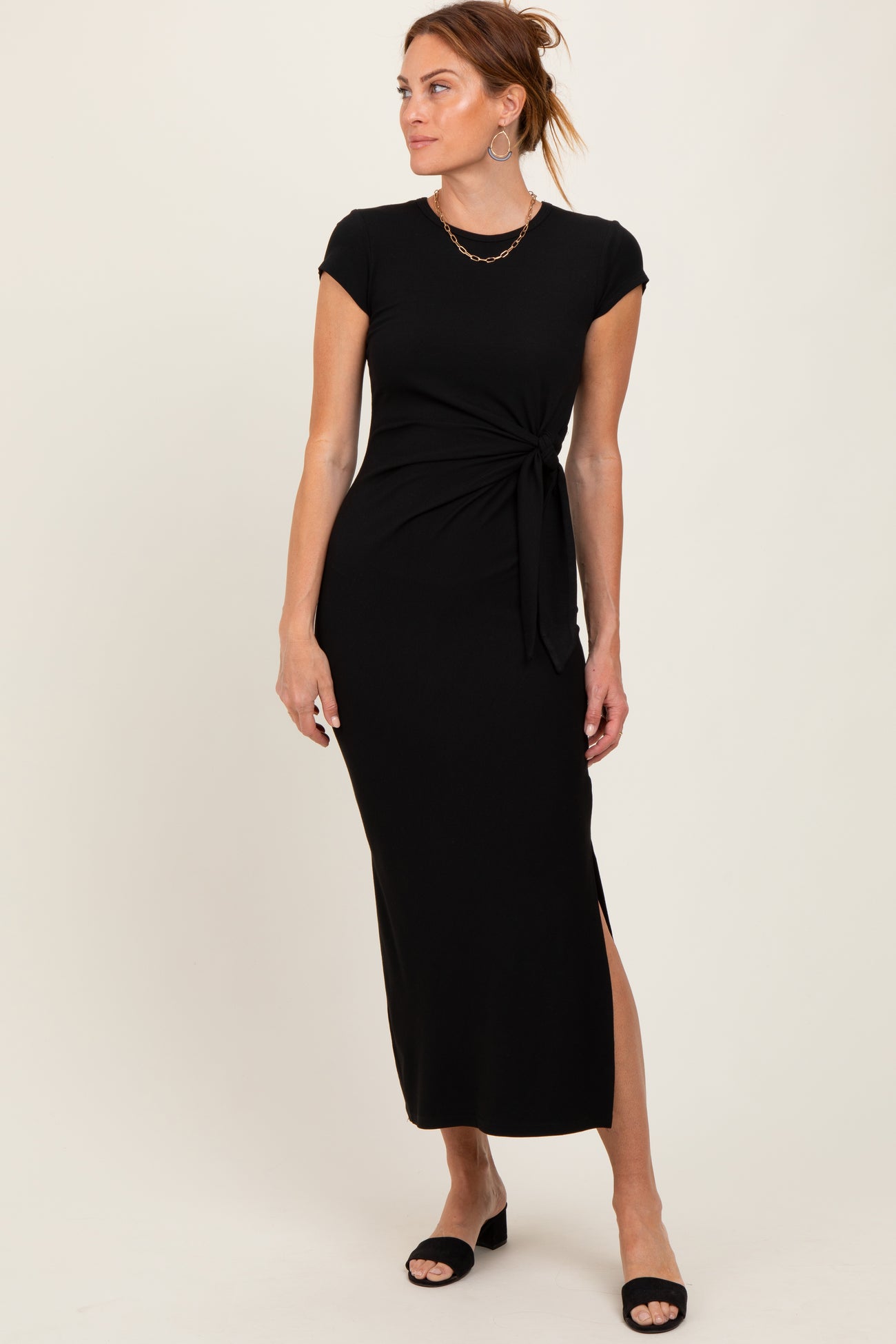 woman wearing a black cap sleeve maxi dress with a knotted waist detail and side slit