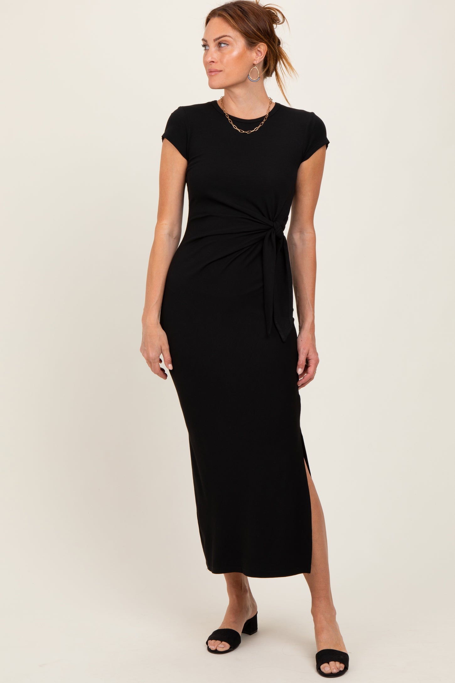 woman wearing a black cap sleeve maxi dress with a knotted waist detail and side slit