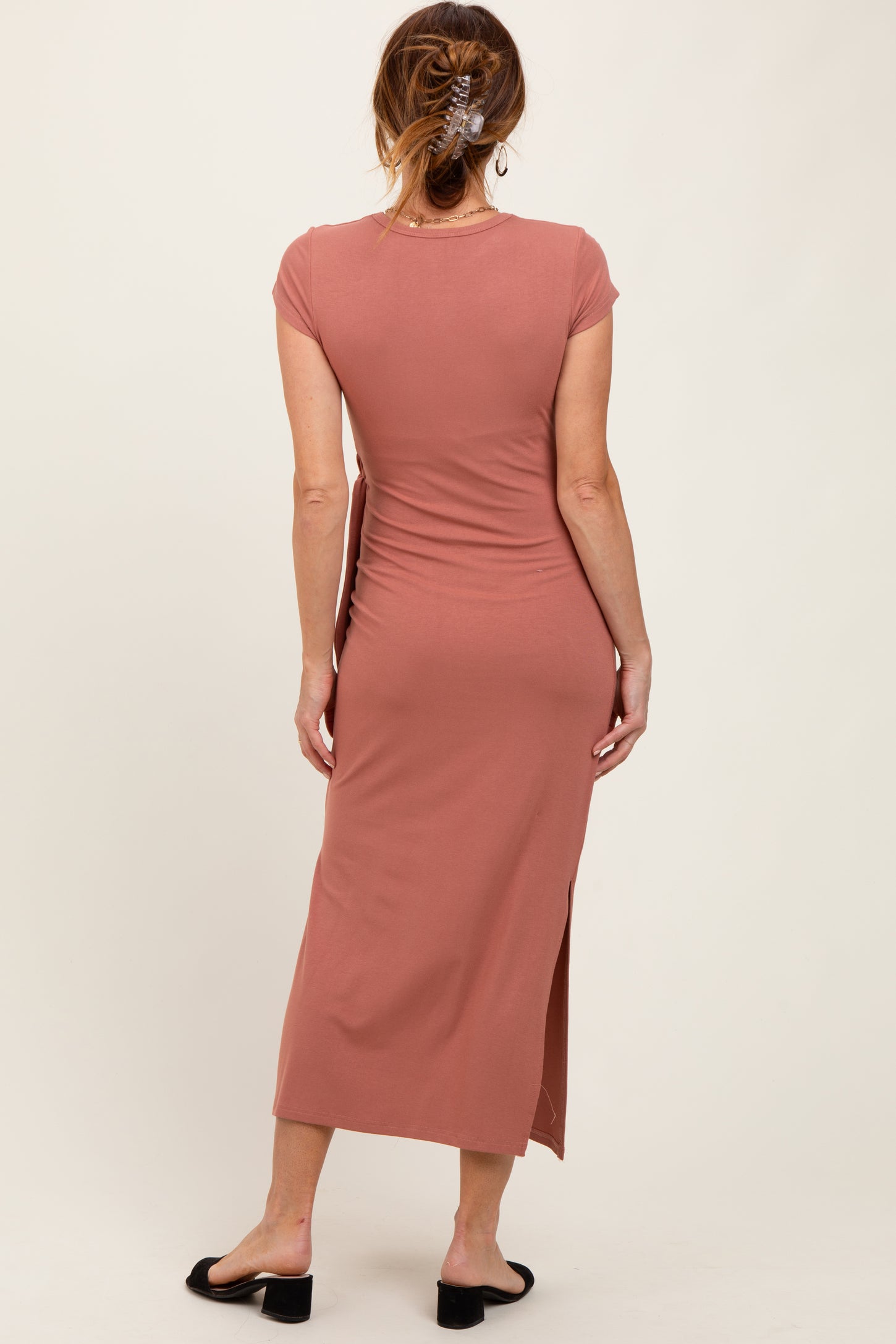 woman wearing a dusty rose cap sleeve midi dress with a slit at the side, viewed from the back
