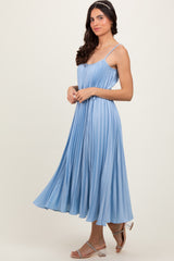 woman wearing a blue pleated midi dress with spaghetti straps and a flowy skirt, standing against a neutral background