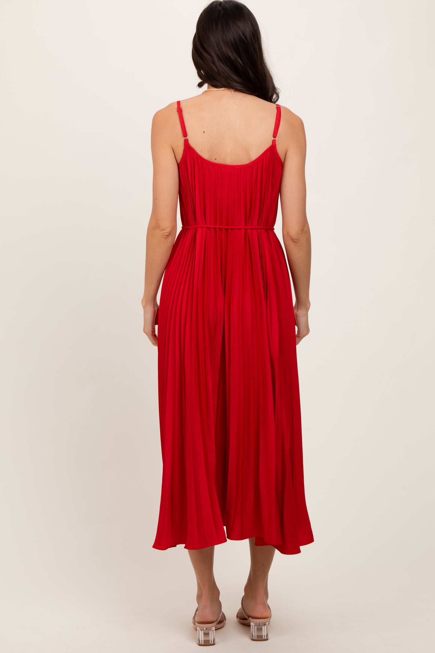 woman wearing a red pleated midi dress with spaghetti straps, viewed from the back