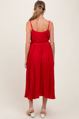 woman wearing a red pleated maternity dress with adjustable straps, showing the back view and a flowing silhouette