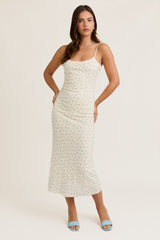 woman wearing a light floral midi dress with spaghetti straps and a fitted silhouette, posing confidently