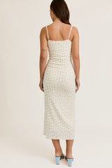 woman wearing a light green spaghetti strap maxi dress with a floral print, seen from the back
