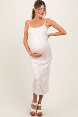 woman wearing a floral print maternity dress with thin straps, holding her baby bump