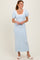 woman wearing a light blue midi dress with puff sleeves and bow details on the shoulders
