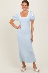 woman wearing a light blue midi dress with puff sleeves and white shoulder ties, standing with one hand on her hip