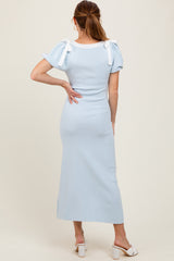 woman wearing a light blue fitted midi dress with short puff sleeves and bow details on the shoulders
