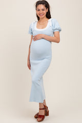 woman wearing a light blue maternity dress with puff sleeves and a square neckline, cradling her baby bump