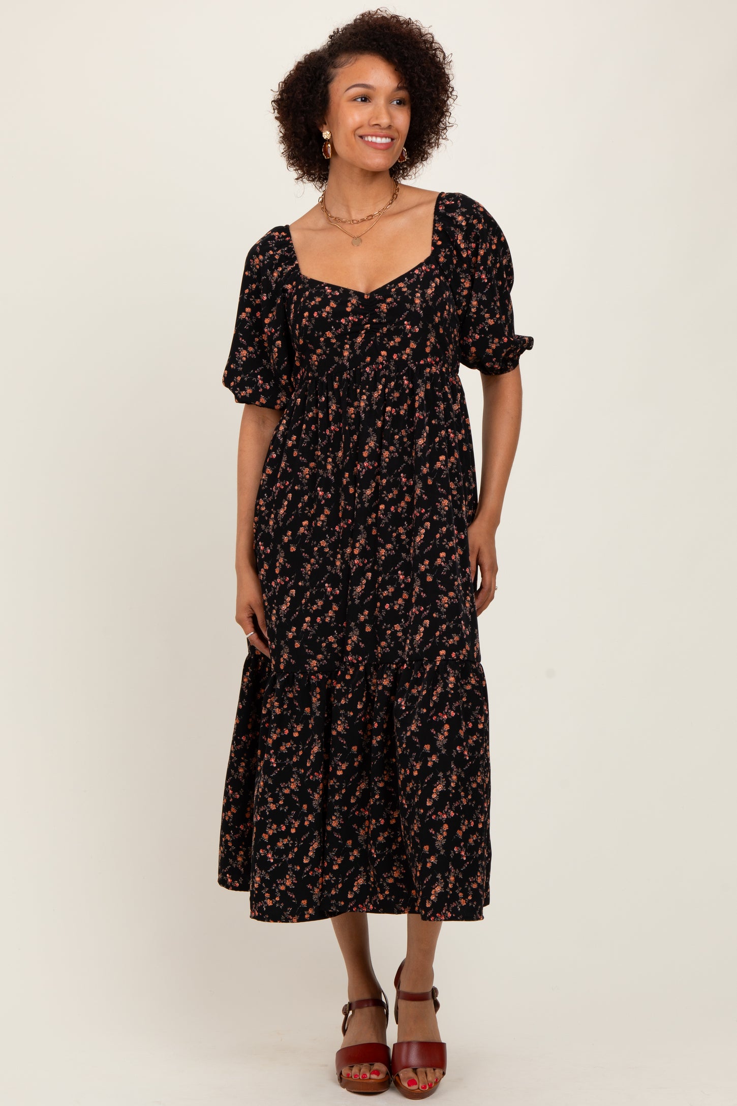 woman wearing a black floral midi dress with puff sleeves and a square neckline