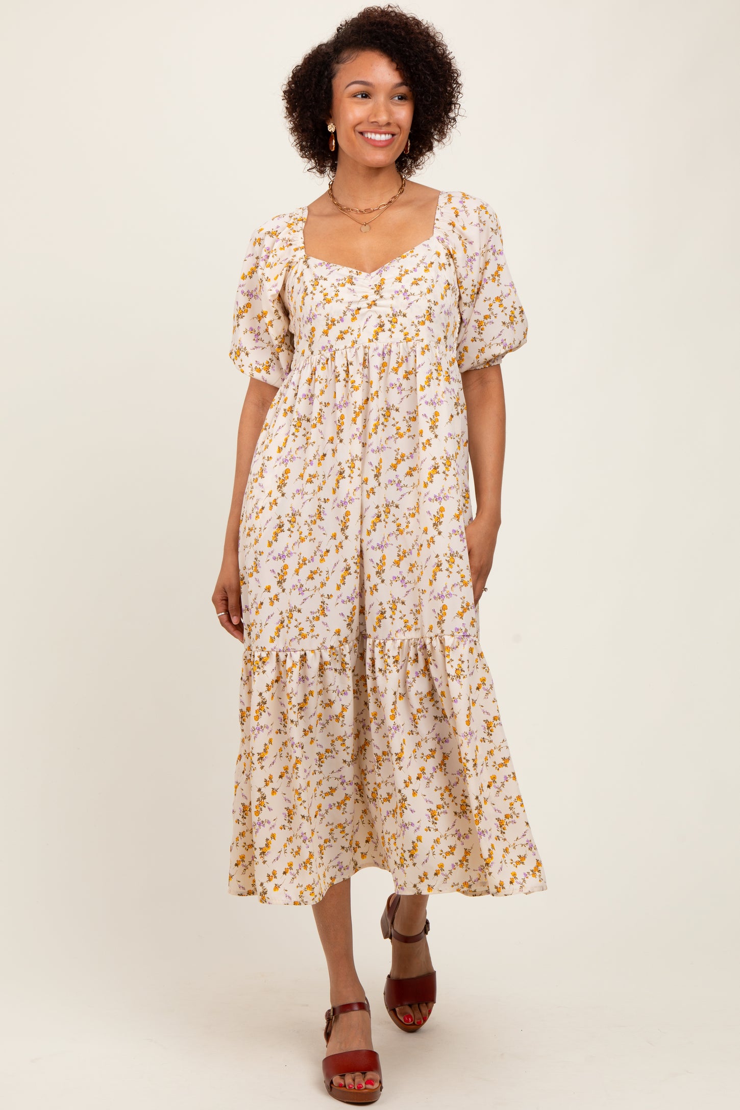 woman wearing a white floral midi dress with puff sleeves and a square neckline, standing and smiling
