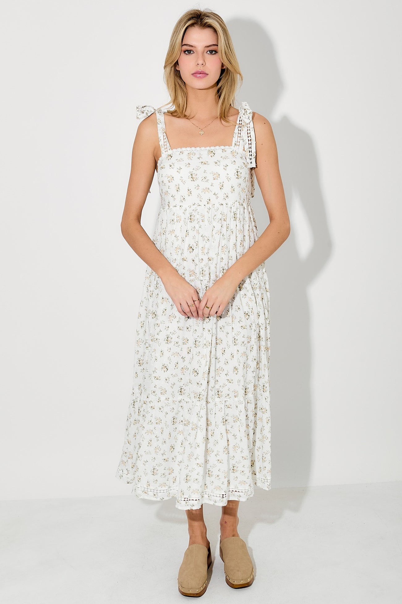 woman wearing a white floral midi dress with bow tie straps and a flowy silhouette