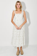 woman wearing a white floral midi dress with bow tie straps and a flowy silhouette