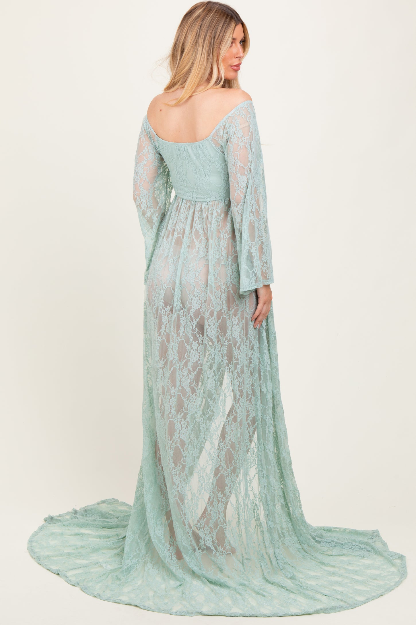woman wearing a sheer mint green lace maternity gown with long sleeves and a flowing skirt